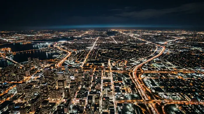 Vue aérienne nocturne d'une mégapole tentaculaire aux lumières s'étendant à l'horizon.