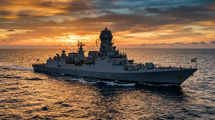 Bâtiment de guerre de la marine indienne patrouillant dans l'océan Indien au coucher du soleil.