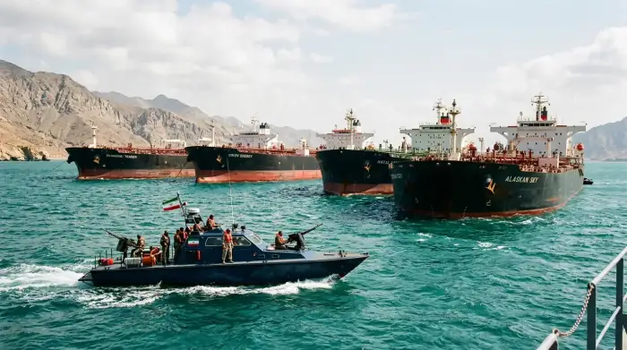 Pétroliers à l'arrêt à l'entrée du détroit d'Ormuz, sous surveillance de vedettes iraniennes, illustrant le blocage du transit énergétique.