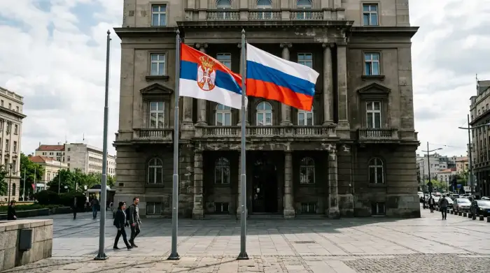 Drapeaux serbe et russe côte à côte devant un bâtiment officiel dans les Balkans.