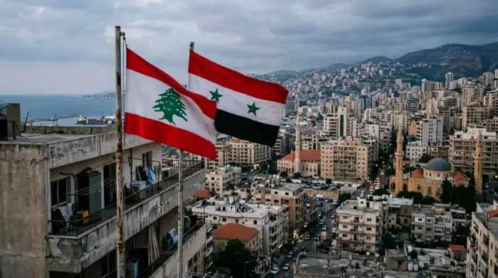 Drapeaux libanais et syrien superposés sur fond de Beyrouth.